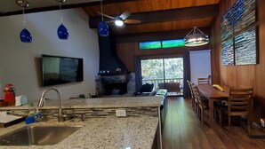 Una cucina moderna con piani di lavoro in granito, piano cottura integrato e zona pranzo con sedie e tavolo in legno.