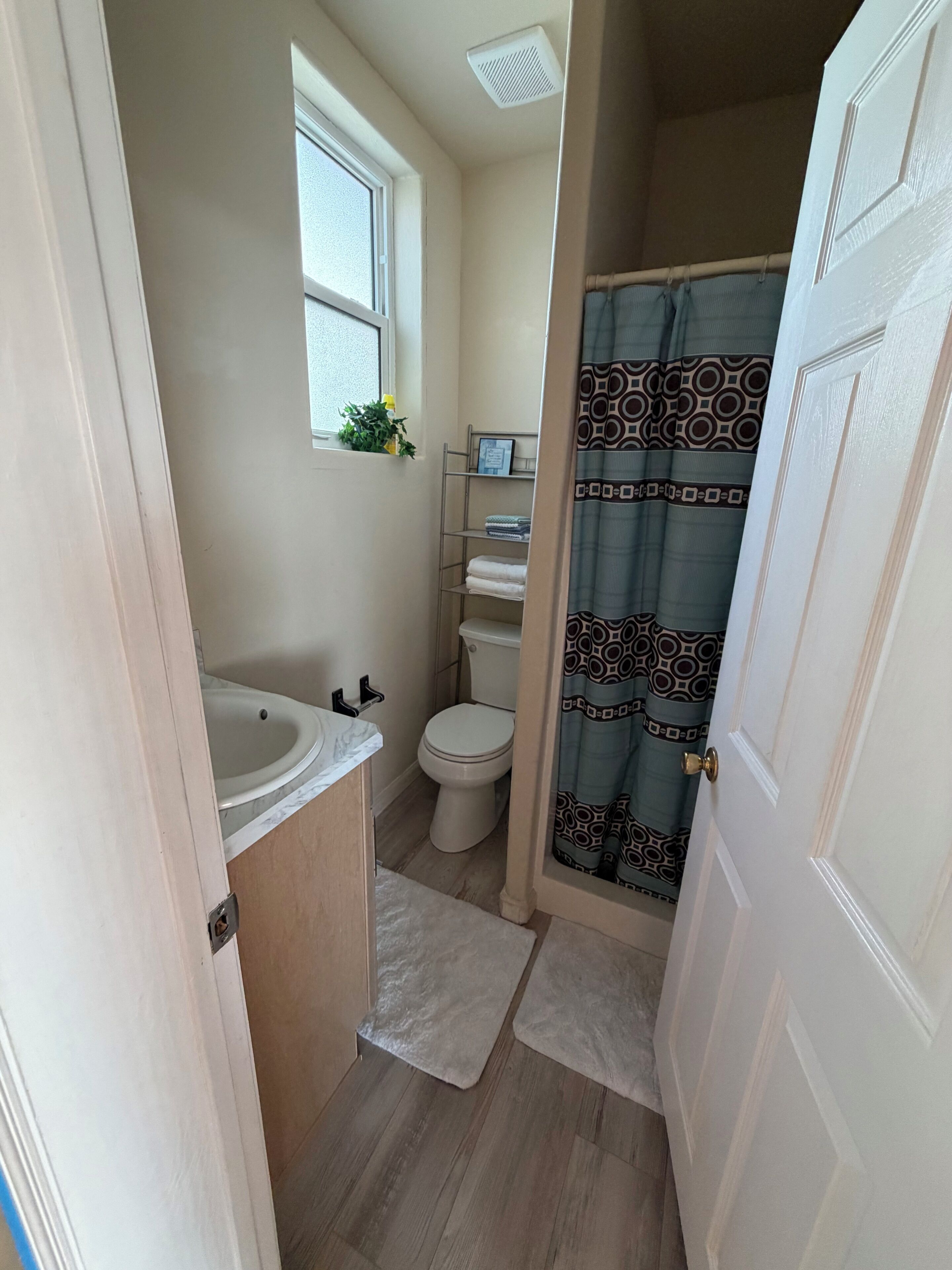 A compact bathroom with a sink, toilet, and shower curtain.