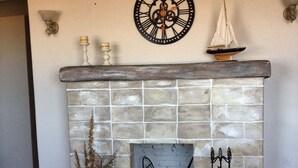 A fireplace with a tiled surround, a decorative clock, and a small sailboat ornament above it. - Beachfront Spanish Style Landmark 3 Bedroom 2 bath House (Flagler Beach)