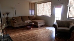 A living room with a wooden floor, a sofa, a chair, and a coffee table. - Beachfront Spanish Style Landmark 3 Bedroom 2 bath House (Flagler Beach)