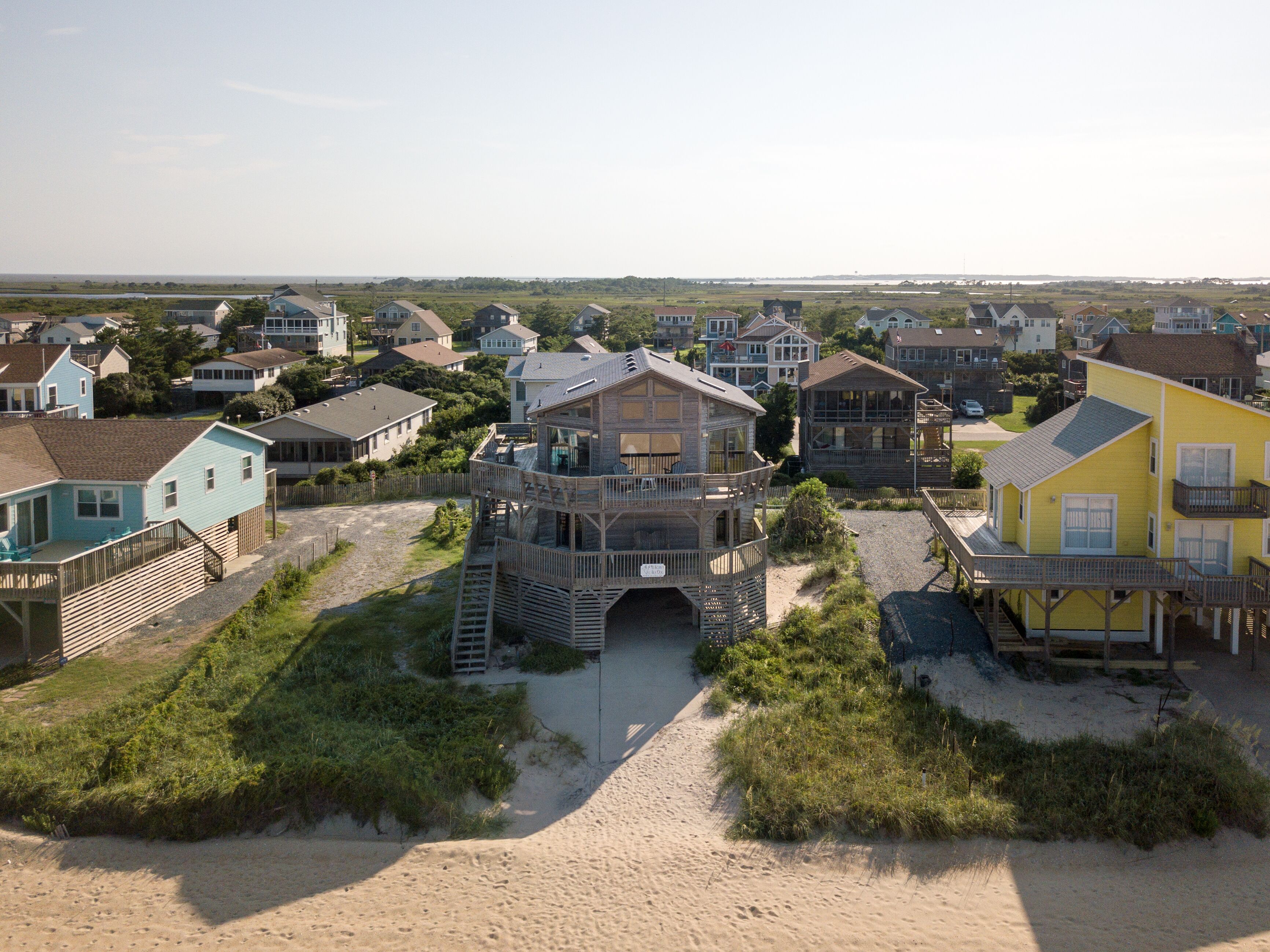 Una zona residencial costera con casas que tienen balcones y una estructura de madera destacada con una plataforma de observación.