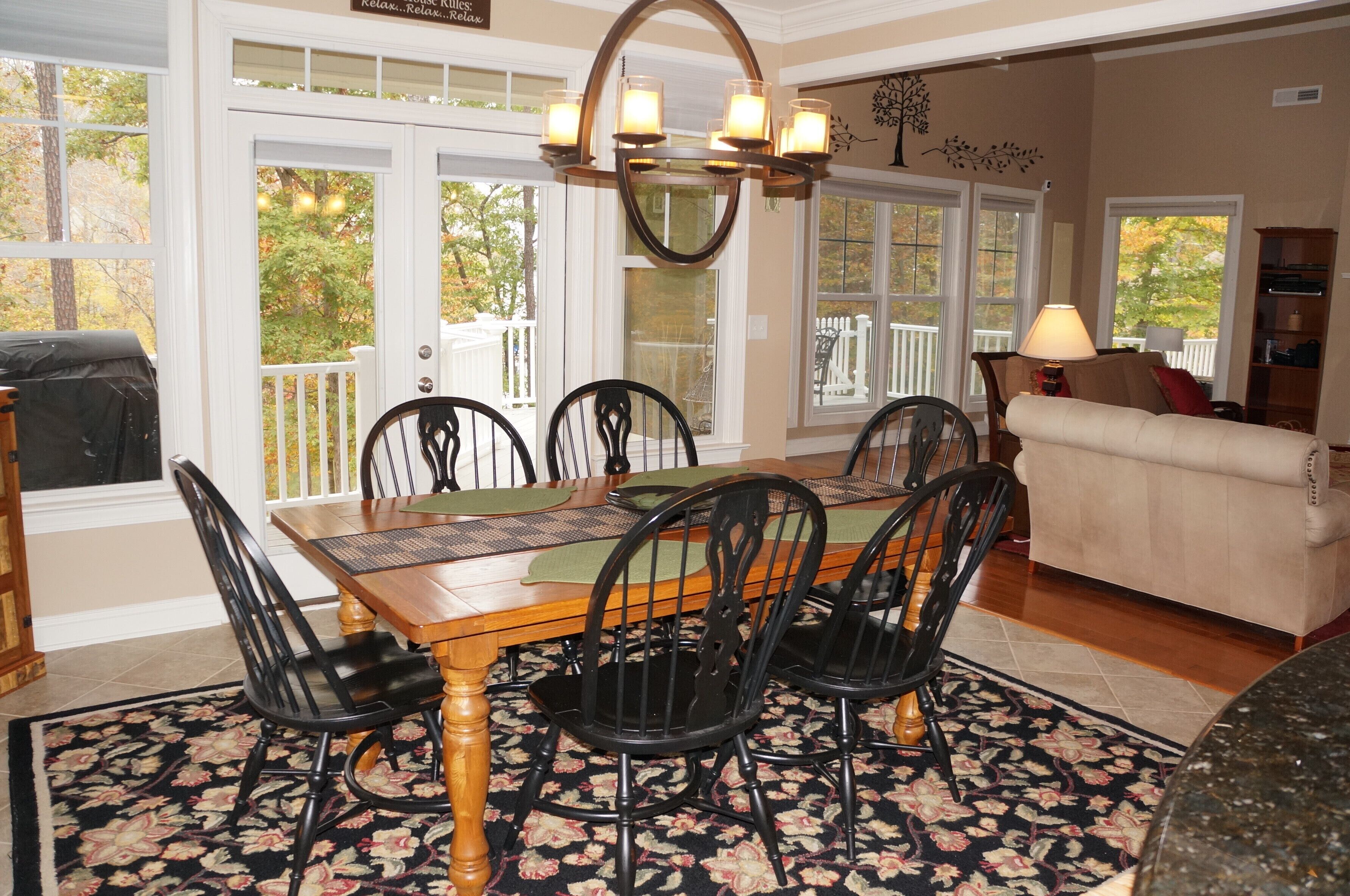 Un coin repas avec une table en bois, des chaises noires et un lustre.