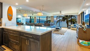A modern kitchen with dark wood cabinets, a large island, and a view of the ocean.