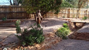 A garden with a statue, a wooden fence, and a small bridge over a dry stream. - Relaxing, Spiritual, Meditative Residential House - Large yard!  MONTHLY RENTAL. (Sedona)