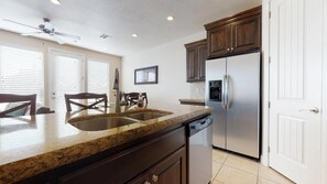 A kitchen with granite countertops, stainless steel appliances, and dark wooden cabinets.