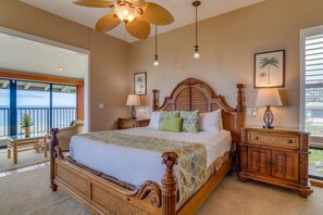 A spacious bedroom with a large bed, a wooden headboard, two bedside tables, and a ceiling fan. - Kapalua Bay Villa 33B3  Oceanfront Views (Lahaina)