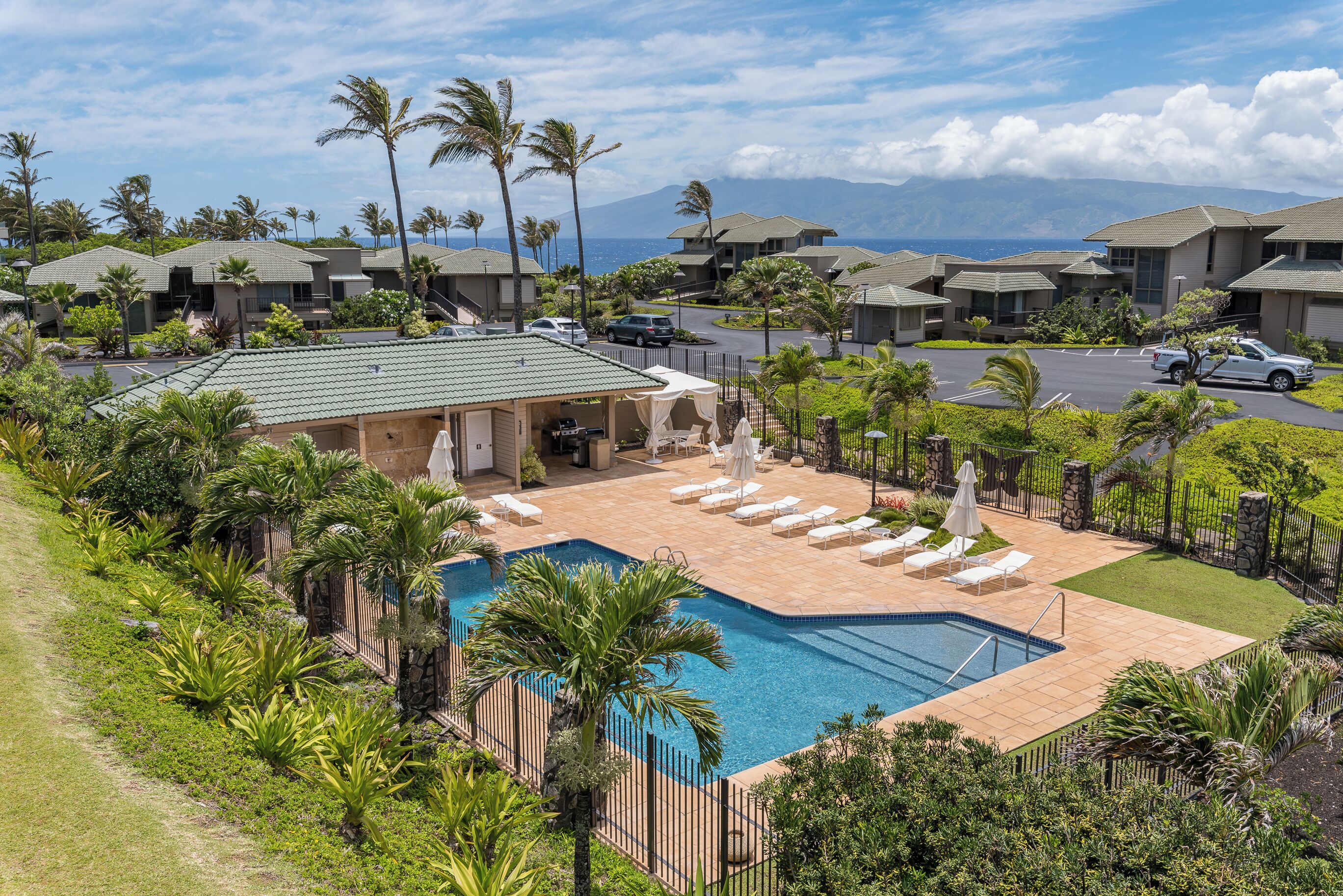 A resort with a swimming pool, lounge chairs, and palm trees.