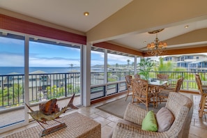 A spacious balcony with a view of the ocean, wicker furniture, and a decorative fish sculpture.