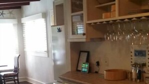 Una cocina con armarios de madera, una encimera y un comedor con una silla y una mesa.