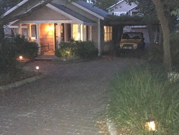 Une maison avec un porche, une allée et un véhicule garé devant.