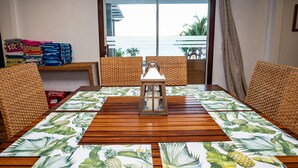 A wooden table with a tropical print tablecloth, wicker chairs, and a lantern.