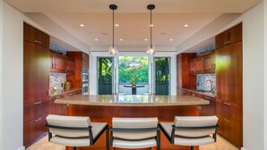 Una cocina moderna con una isla central, taburetes de bar e iluminación colgante.