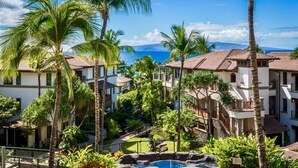 Un resort con varias construcciones, palmeras y una piscina.