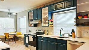 A modern kitchen with dark cabinets, a built-in oven, and a dining area with a yellow chair and table. - 4BR/4BA Quiet Central Frisco Home - Near Star Center, UNT, Toyota Sta. + Hot Tub (Frisco)