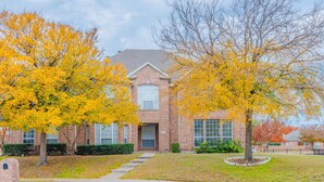A two-story brick building with a central entrance, surrounded by well-maintained lawns and trees with yellow leaves. - 4BR/4BA Quiet Central Frisco Home - Near Star Center, UNT, Toyota Sta. + Hot Tub (Frisco)