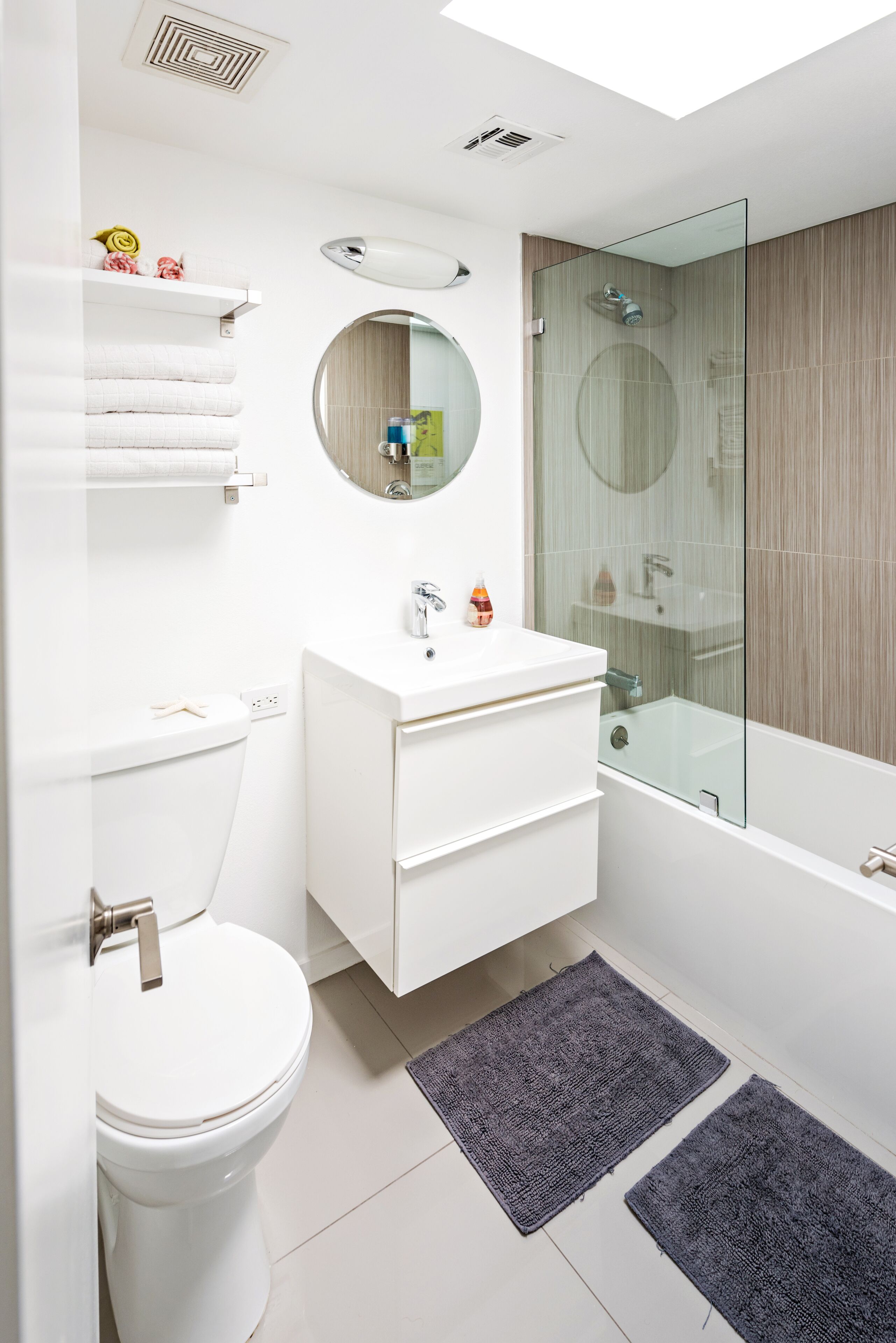 A modern bathroom with a toilet, sink, mirror, and glass-enclosed shower.