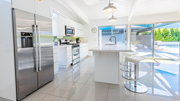 A modern kitchen with stainless steel appliances, a central island, and a view of the outdoors. - Beautiful! Remodeled Mid-Century Alexander w/ SALTWATER pool, spa, bikes, & more (Palm Springs)