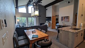 Een moderne keuken met een houten eiland, een eethoek met een grote tafel en stoelen, en een gezellige zithoek met een bank en fauteuils.