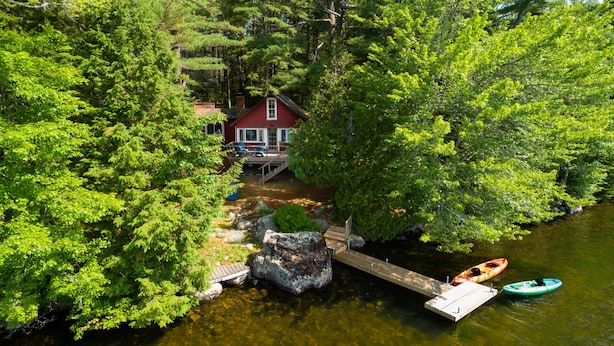 A cabin with a dock extending into a river, surrounded by dense forest.