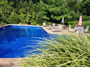 A rectangular swimming pool with a tiled edge, surrounded by lush greenery and outdoor furniture. - NOFO  ESCAPE relax-swim-enjoy. Bachelorettes-Weddings-Family vacation (Greenport)