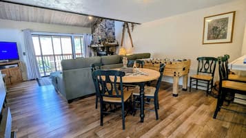 A cozy living room with a sofa, a round table, and a foosball table.