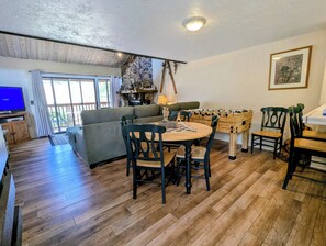 A cozy living room with a sofa, a round table, and a foosball table.