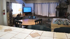 Una sala de estar con una mesa de futbolín, un televisor y una chimenea.