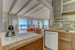 A modern kitchen with a view of the ocean, a dining area with a sofa, and a kitchen island. - Beautiful Beach Front Studio (La Jolla)