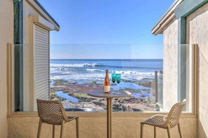 A balcony with two wicker chairs, a small round table with a bottle and glasses, and a view of the ocean. - Beautiful Beach Front Studio (La Jolla)