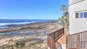 A coastal view with a wooden deck overlooking a rocky beach and ocean.