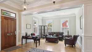 A spacious living room with a wooden floor, a black leather sofa, a coffee table, and a patterned rug. - Tons of Space & Gorgeous Porch! (Savannah)