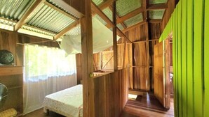 Ein Zimmer mit Holzboden, einem Bett, einem Ventilator und einer grünen Wand.