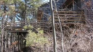 Eine rustikale Holzhütte mit einer Holzterrasse und einer kleinen Brücke.