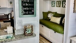 A cozy room with a bed, a small table, and a kitchen area. - OCEANFRONT -  “Little piece of paradise” @ 206 Windsong in Windy Hill, N. Myrtle (North Myrtle Beach)