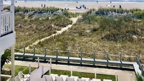 A beach view from a balcony with a clear sky, a sandy beach, and a pathway leading to beach chairs. - OCEANFRONT -  “Little piece of paradise” @ 206 Windsong in Windy Hill, N. Myrtle (North Myrtle Beach)