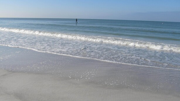 Ein Strand mit sanften Wellen und blauem Himmel.