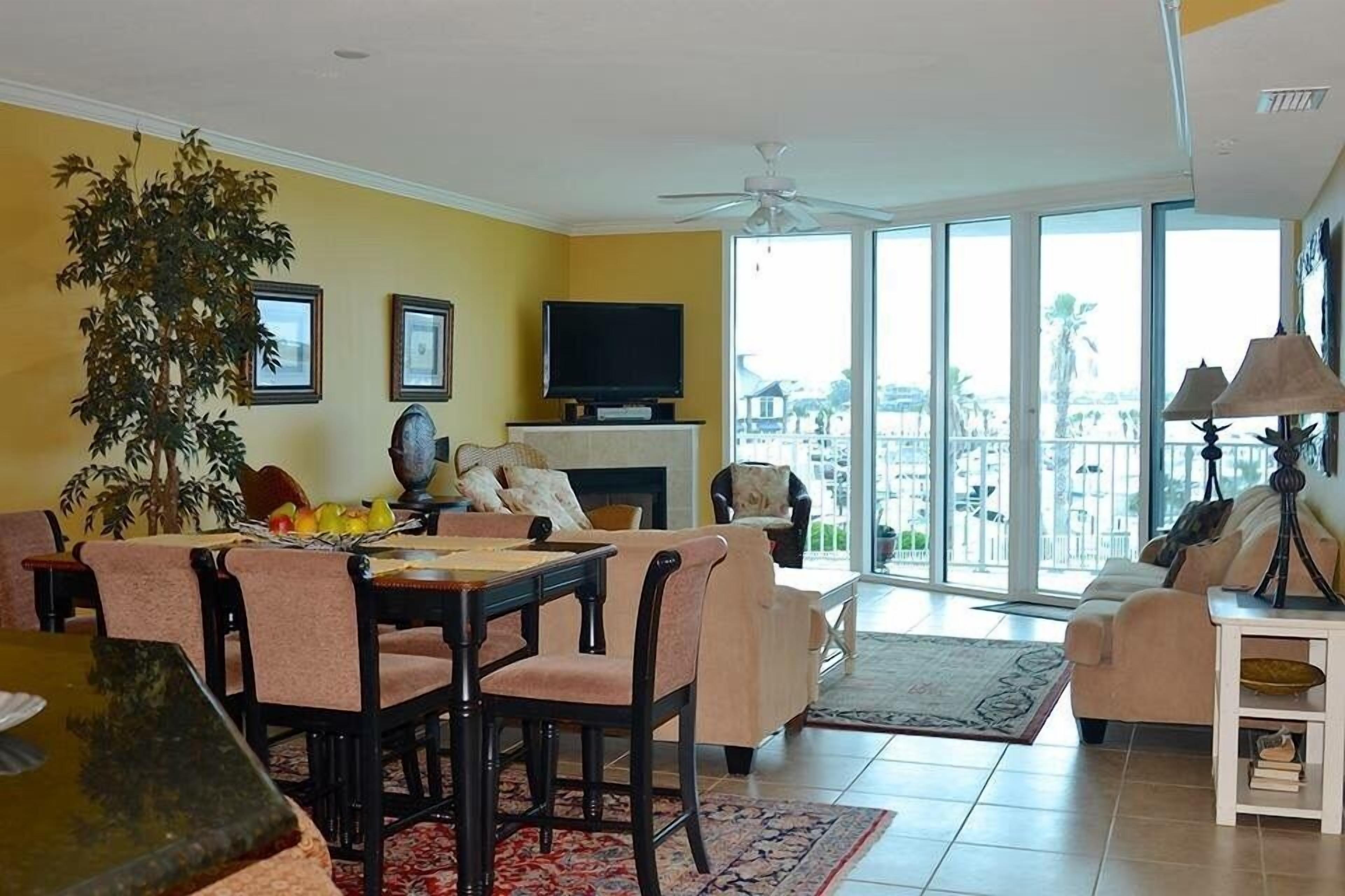 A living room with a dining area, a fireplace, and a large window with a view.