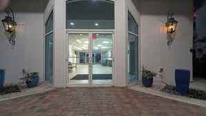 A building entrance with a glass door, two potted plants, and a brick pathway leading to the entrance. - Relax & Enjoy - Coastal Paradise!  SUNDAY- SUNDAY RENTAL ONLY DURING PEAK SEASON (Orange Beach)