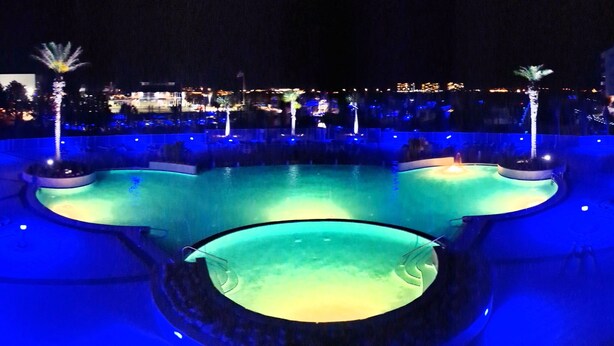 A nighttime pool area with illuminated water features and seating areas. - Relax & Enjoy - Coastal Paradise!  SUNDAY- SUNDAY RENTAL ONLY DURING PEAK SEASON (Orange Beach)