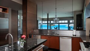 A modern kitchen with a view of the ocean, featuring dark wood cabinets, granite countertops, and stainless steel appliances. - LARGE CONTEMPORARY HOME ON THE SAND, HOT TUB, CHEF’S KITCHEN, ENDLESS VIEWS (Capistrano Beach)