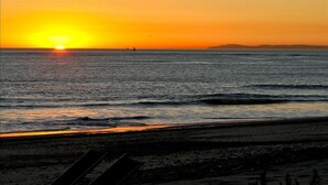 A sunset over the ocean with a beach in the foreground. - LARGE CONTEMPORARY HOME ON THE SAND, HOT TUB, CHEF’S KITCHEN, ENDLESS VIEWS (Capistrano Beach)