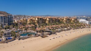 A resort with multiple buildings, a large pool, and a beach with umbrellas. - 3rd Night Free-Luxury Oceanview HBC Resort Residence-Medano Beach (Cabo San Lucas)