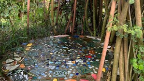 Un área con mosaicos rodeada de follaje denso y estructuras de bambú.