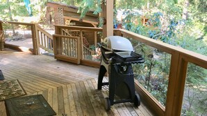 Eine Holzterrasse mit Grill und einem hölzernen Spielhäuschen.