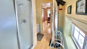 A hallway with a glass shower door, a metal bench, and a fireplace.