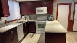 A modern kitchen with dark wood cabinets, a white microwave, a stove, and a coffee maker.