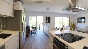 A modern kitchen with a central island, built-in appliances, and a dining area with a view to the outdoors.