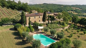 Une villa en pierre dotée d’une piscine, entourée d’une végétation luxuriante et d’oliviers.