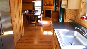 A wooden interior with a kitchen area including a refrigerator, sink, and dining table with chairs. - Woodland secluded cabin on 7 acres, with private dock and kayaks (Leitchfield)