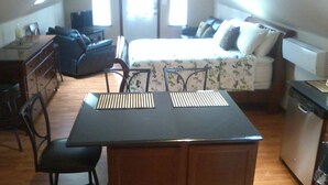 A compact room with a bed, a small kitchenette, a dining area, and a window.